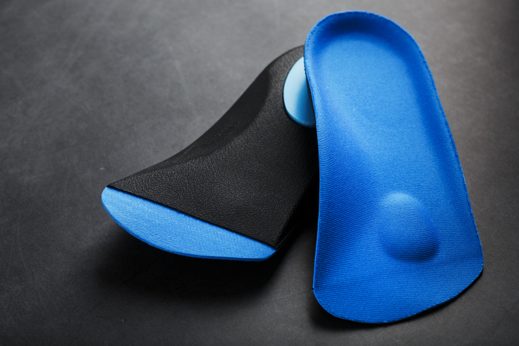 orthopedic-insoles-correction-blue-color-foot-black-background-free-space